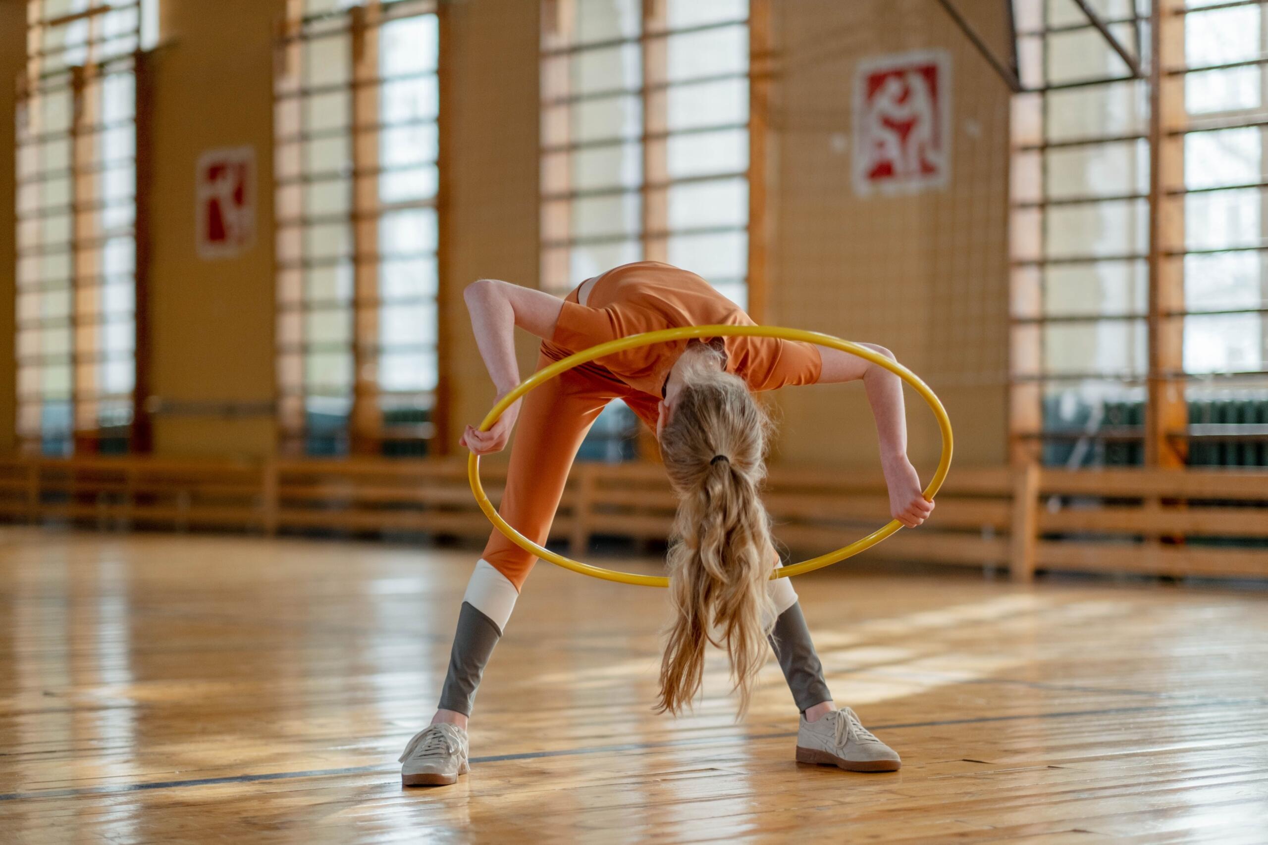young girl doing a gymnastics routine with a hula hoop