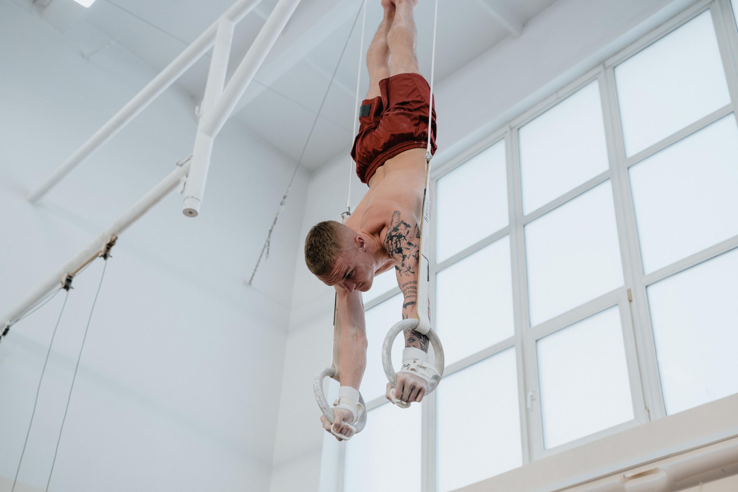 man holding himself upside down on gymnastics rings