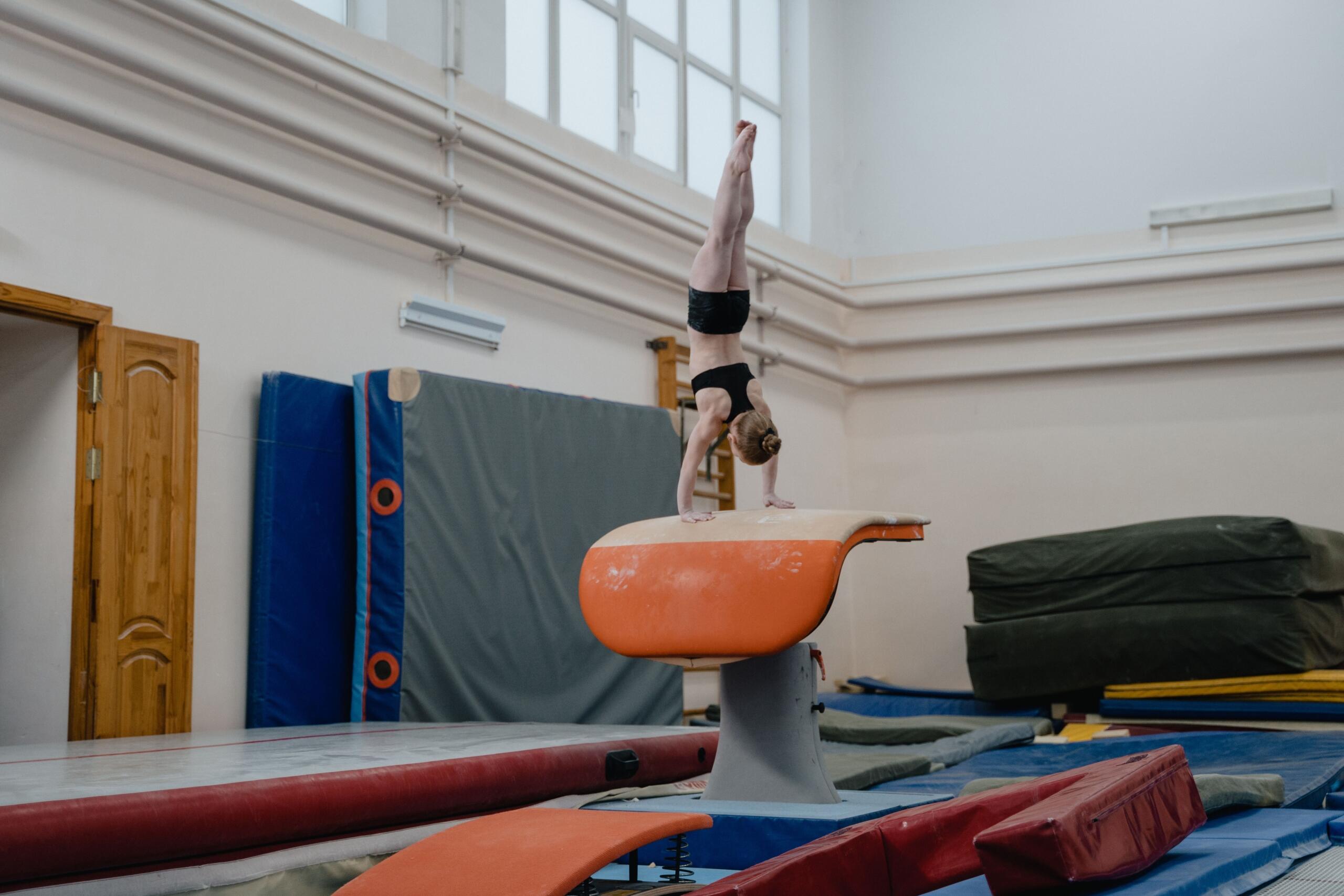 young girl doing a handstand on a balance beam