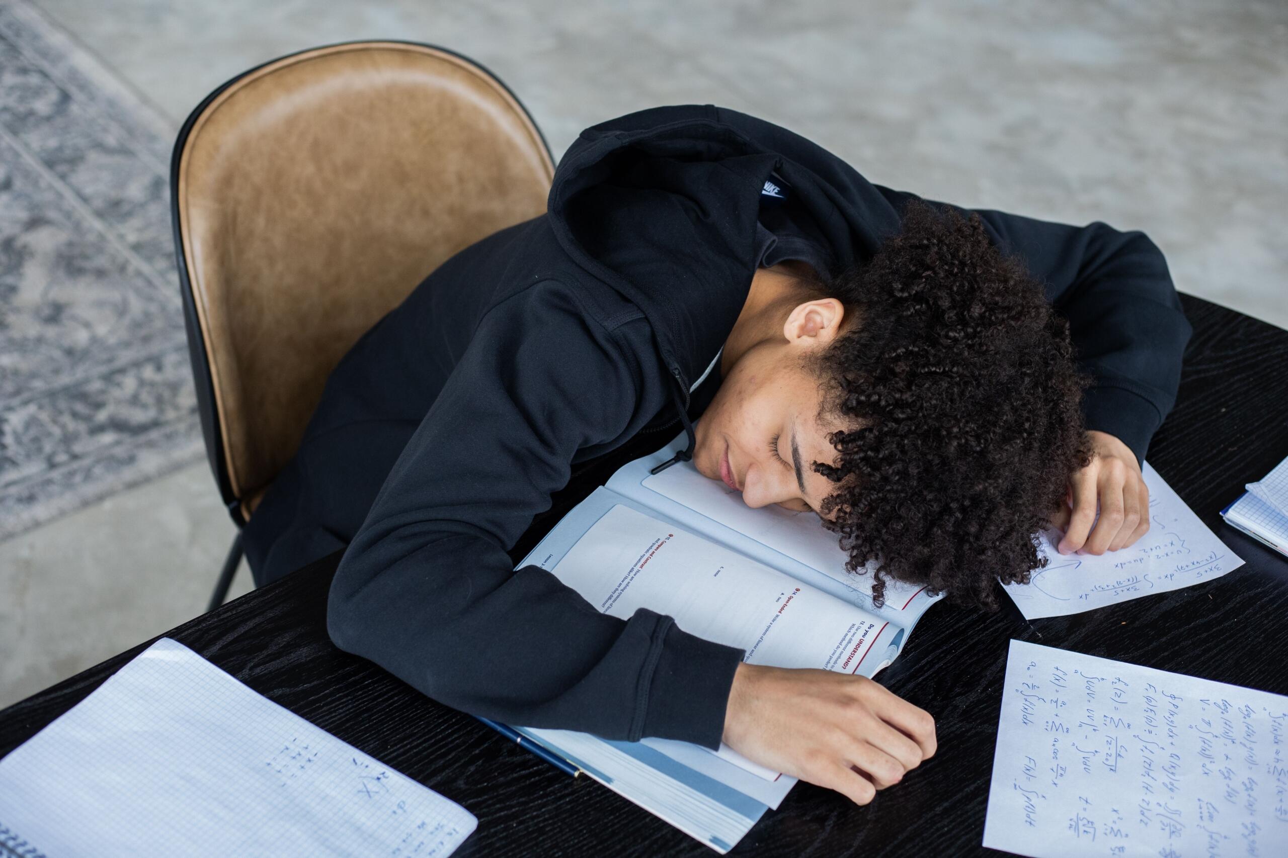 Student asleep while studying with books and notes nearby.