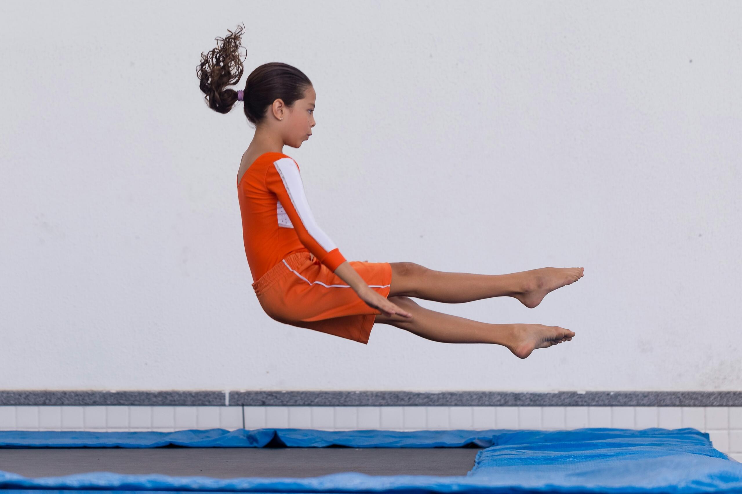 girl wearing leotard and shorts bouncing on a trampoline