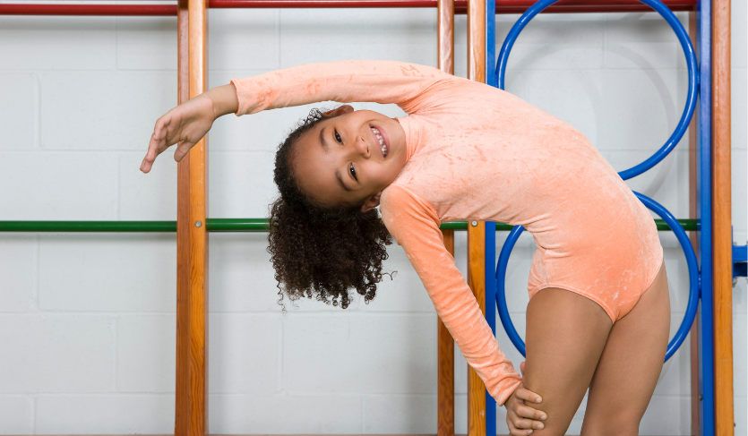smiling gymnastics student doing a side bend
