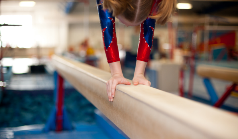 close up of the hands of a gymnast doing a handstand on a balance beam